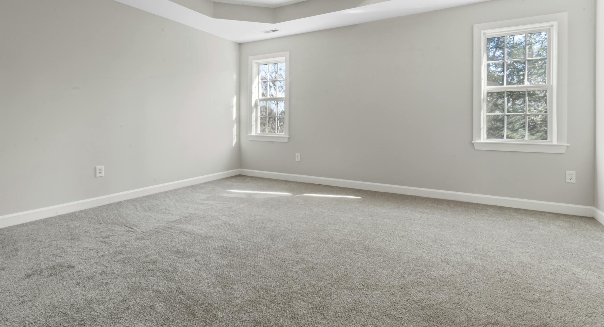 Bright empty room featuring modern ceiling lamp and large windows.