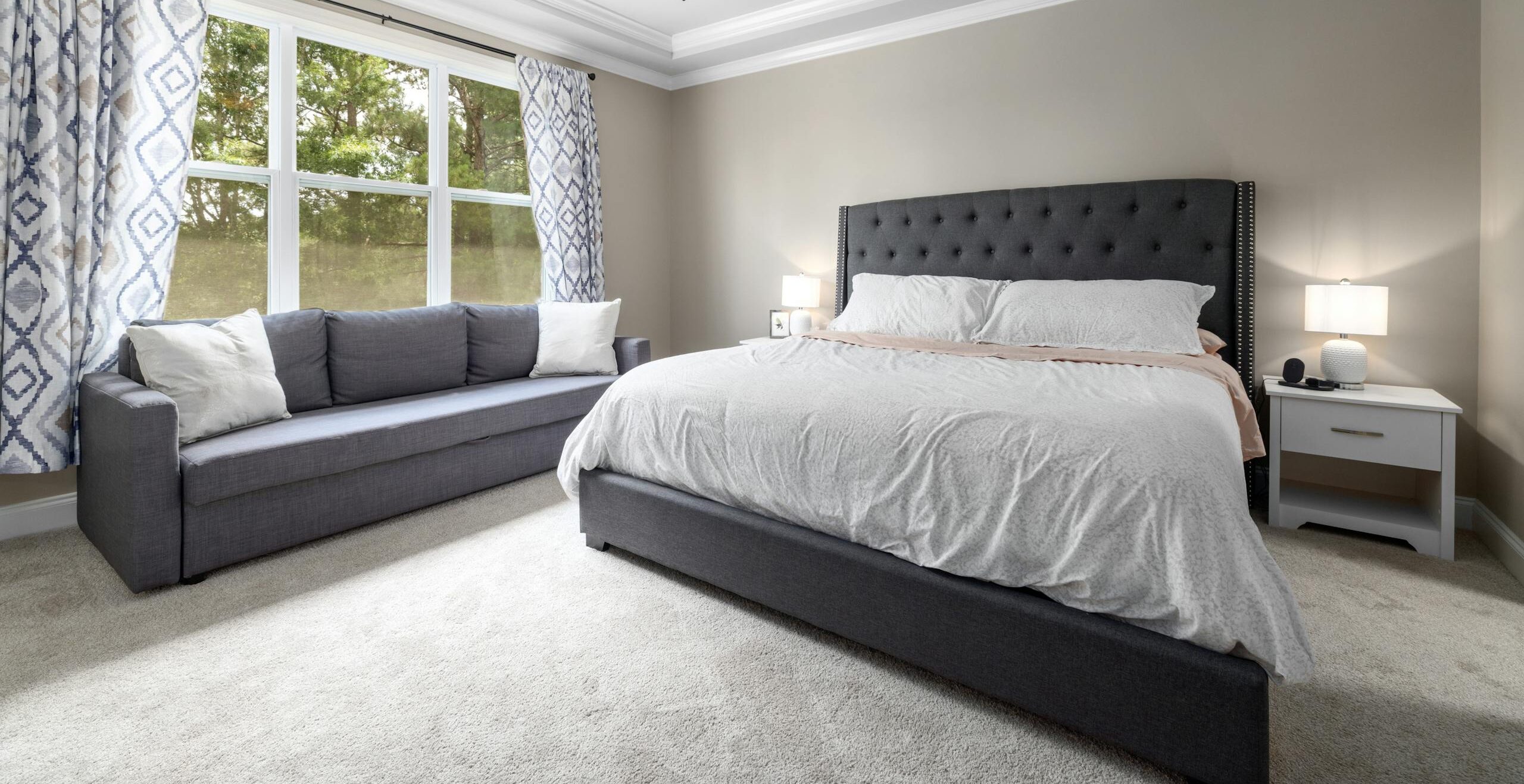 Minimalist bedroom featuring a king-sized bed, elegant furniture, and natural light through large windows.